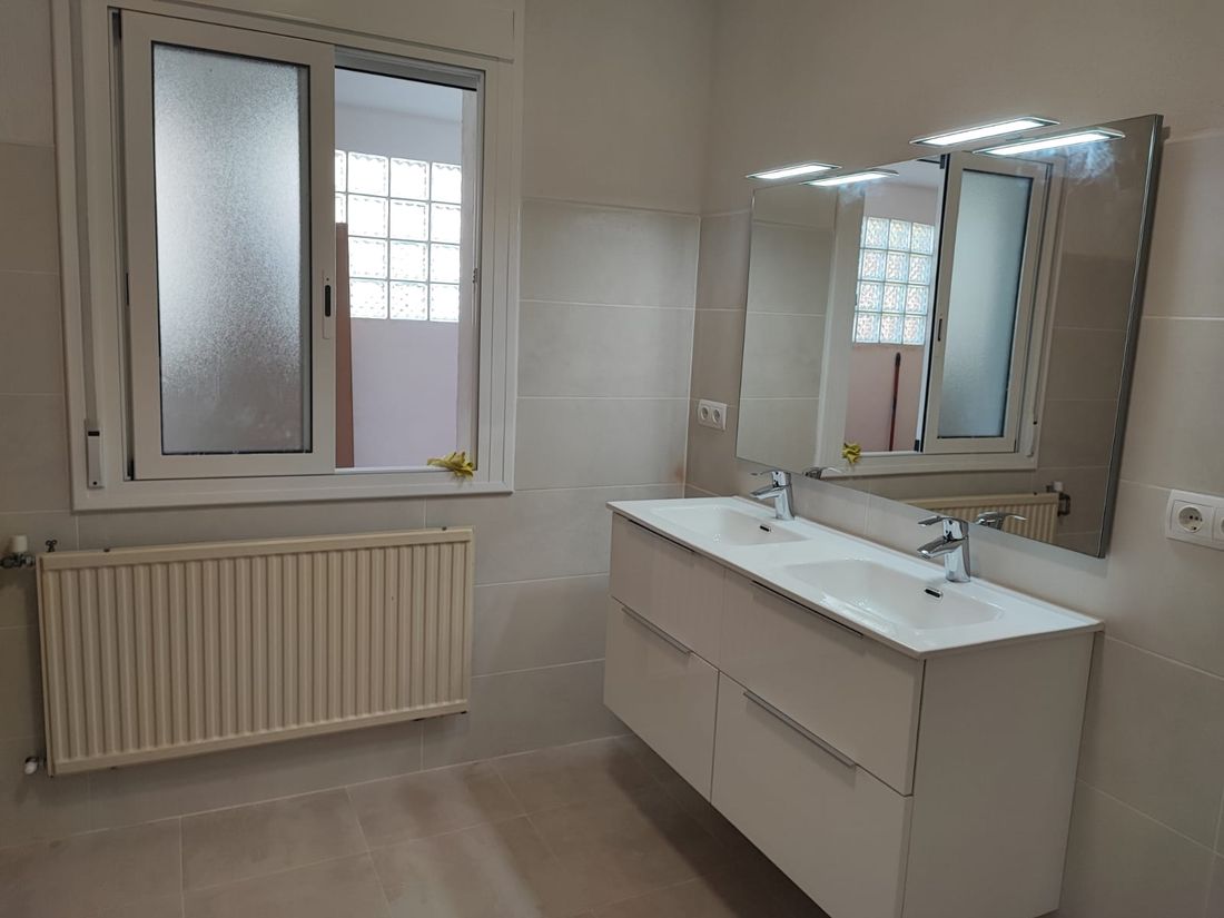 Bany reformat amb radiador de calefacció i doble lavabo